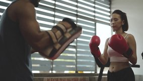 Female boxer practicing punches with coach holding pads in gym. Focused woman training for fitness, self-defense, and strength. Indoor boxing session enhancing technique and confidence. - Powered by Shutterstock - Get 15% off with code: PIKWIZARD15