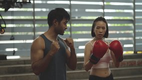 Female boxer training with male coach in gym. Woman wearing red boxing gloves practicing punch technique with personal trainer. Indoor fitness session focused on strength, form, and endurance. - Powered by Shutterstock - Get 15% off with code: PIKWIZARD15