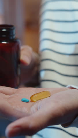 Vertical Screen : Sick asian young lady holding pill take a look medicine sit on couch at home night. Girl taking medicine after doctor order, quarantine at home, social distancing healthcare concept.