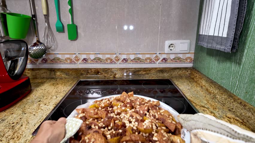 Baker carefully placing freshly baked apple pie inside preheated oven, wearing protective mitts and using cloth to handle hot pastry without burning hands