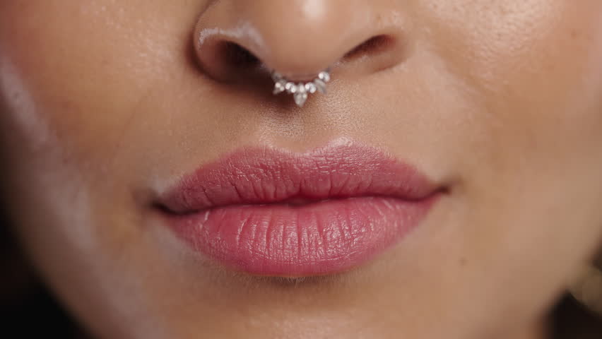 Close-up of smiling biracial woman with septum piercing and natural lips. Beauty, self-love, authenticity, modern femininity.