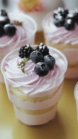 Small cheesecake with blueberries and blackberries close up, sweet dessert, sweet candy bar at a wedding, candy bar decorated with flowers, slow motion. Vertical motion