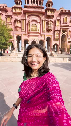 4K vertical selfie video of Indian woman wearing traditional saree and vlogging at Patrika Gate in Jaipur, Rajasthan, India. Travel blogger making content on location. Old Indian architecture.