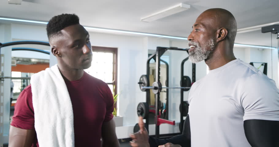 African American trainer and client reacting to tablet prompt tapping plan showing targets at gym. Fitness, mentorship, motivation, technology, strength, wellness, coaching