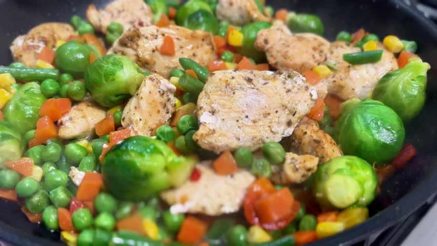 Chicken pieces mixed with vibrant vegetables cooking in skillet, creating a delicious stir fry. Ideal for home kitchen or meal prep services. Concept of healthy eating, cooking, family meals.