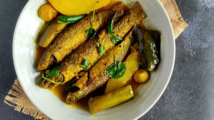 Traditional Bengali Parshe Macher Jhol with potatoes and eggplant simmered in a light mustard gravy. Ideal for food videos, magazines, or restaurant promos.
