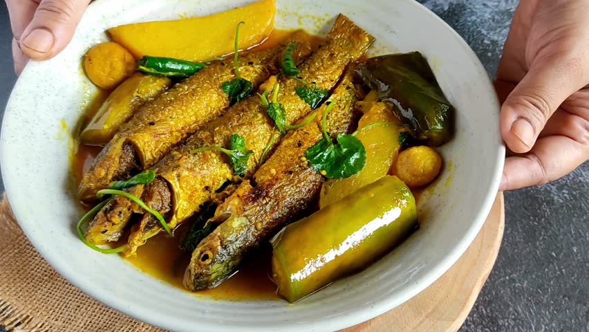 Traditional Bengali Parshe Macher Jhol with potatoes and eggplant simmered in a light mustard gravy. Ideal for food videos, magazines, or restaurant promos.