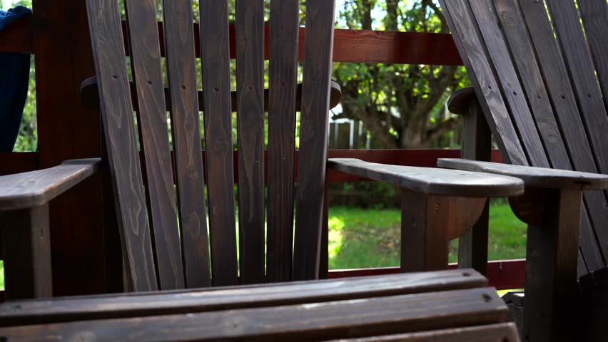 Slow pan shot, adirondack chairs on wooden patio.