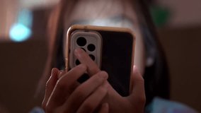 Asian girl is looking at her mobile phone in low light and the blue light from the phone is harmful to her eyes. Cute girl is looking at smartphone on sofa late at night, screen addiction in children. - Powered by Shutterstock - Get 15% off with code: PIKWIZARD15