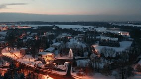 An Aerial view of a snowy village at dusk with festive lights and warm houses during the winter season - Powered by Shutterstock - Get 15% off with code: PIKWIZARD15