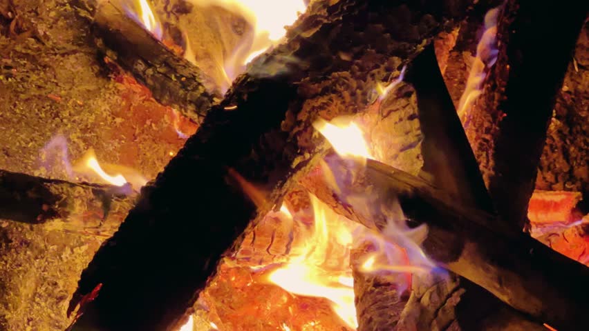 Astrakhan Region,Russia: A campfire on a sandy beach on the banks of the Volga River. A burning campfire on the banks of the Volga River in complete darkness. Sparks from the campfire, flames at night