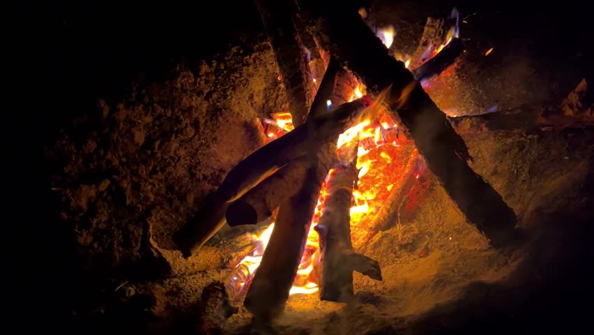 Astrakhan Region,Russia: A campfire on a sandy beach on the banks of the Volga River. A burning campfire on the banks of the Volga River in complete darkness. Sparks from the campfire, flames at night