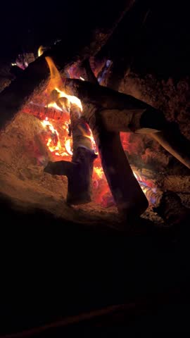 Astrakhan Region,Russia: A campfire on a sandy beach on the banks of the Volga River. A burning campfire on the banks of the Volga River in complete darkness. Sparks from the campfire, flames at night