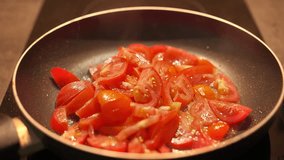 Tomatoes for an omelet are fried in a non-stick frying pan, a cook stirs tomatoes with a wooden spatula, footage for stories about home cooking and culinary inspiration - Powered by Shutterstock - Get 15% off with code: PIKWIZARD15