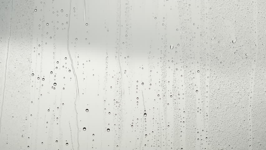 Raindrops flow down the window glass, cloudy sky outside, rainy weather, real-time video about weather forecast and autumn rainy season