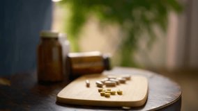 female hand takes a pill, eco vitamins, a wooden board with vitamins, pills, medicines, natural bio supplements, vitamins with herbs, turmeric, home interior, room with green plants 4k cinematic - Powered by Shutterstock - Get 15% off with code: PIKWIZARD15
