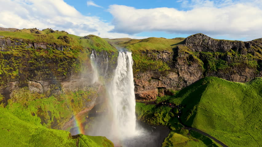 Seljalandsfoss Waterfall in Iceland, highlighted by a beautiful rainbow