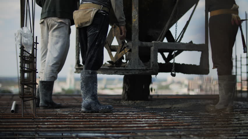 Workers pouring concrete on reinforced slab at construction site