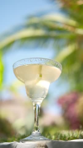 Drinking glass of cocktail decorated lemon slice on table bar, sea on background. Beach bar, summer sea resort concept.