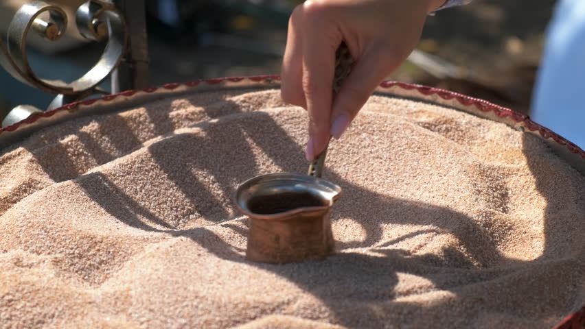 Male hand preparing turkish coffee on sand. Somebody preparing turkish coffee on sand in the urban place