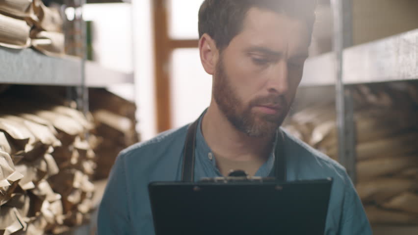 Close up focused Caucasian businessman coffee factory worker small business owner man male holding clipboard write pen check inventory aroma supplies controls storage beans production stock checklist - Powered by Shutterstock - Get 15% off with code: PIKWIZARD15