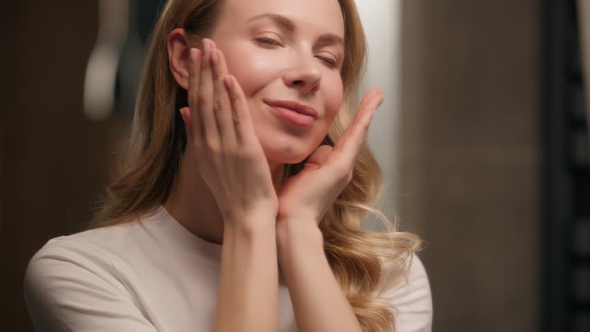 Pretty Caucasian woman look mirror massaging neck face cream beauty routine at home beautiful girl female touching skin applying serum cream lotion moisturizer skincare treatment antiaging cosmetics