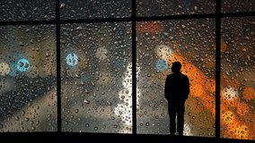 A silhouette of a man stands by a rain-covered window, watching colorful urban lights blur through raindrops at night.
 - Powered by Shutterstock - Get 15% off with code: PIKWIZARD15