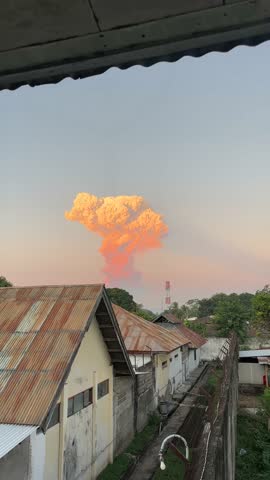 Massive volcanic eruption cloud at sunset, dramatic mushroom-shaped ash plume rising into dark sky. Nature power, disaster concept, perfect for editorial or background use