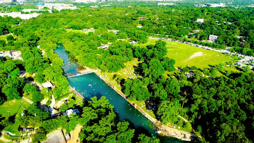 Aerial view of a river flowing through a lush green forest on a sunny day