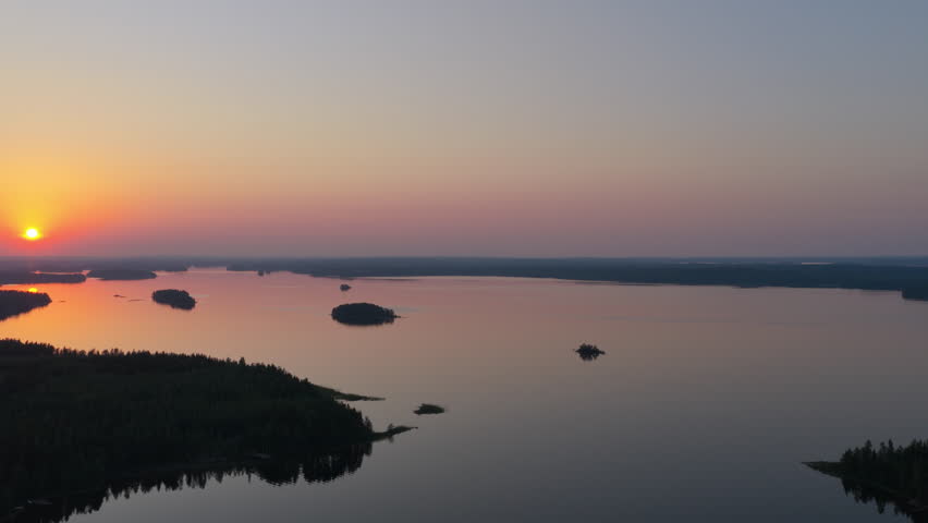 Aerial rising shot rotating over lake Saimaa, beautiful, summer sunset in Finland