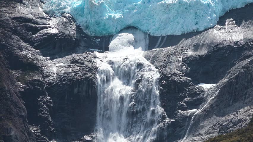 Majestic glacier with waterfall cascading down rocky cliffs in remote wilderness area
