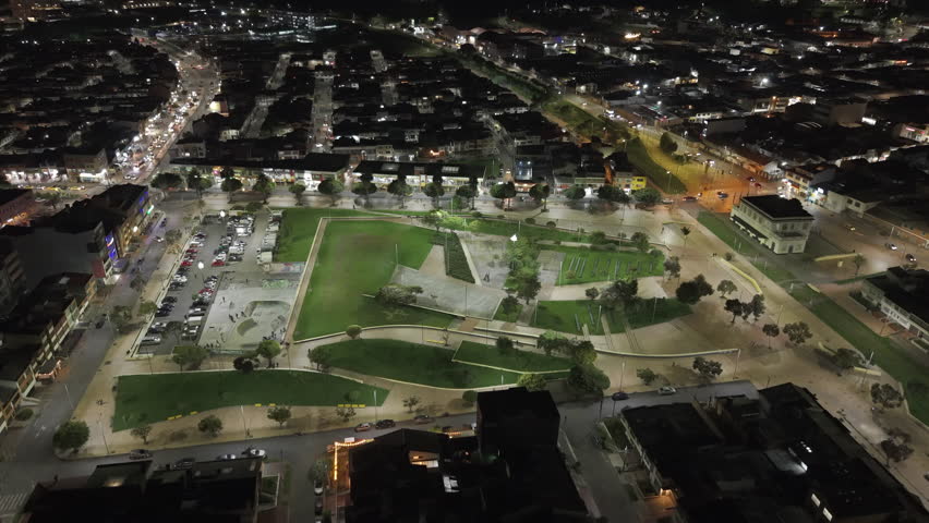 Drone video capturing Zipaquira Parque la Esperanza with sparkling streetlights, vibrant cityscape, and serene park areas at night. A captivating blend of urban and natural elements.