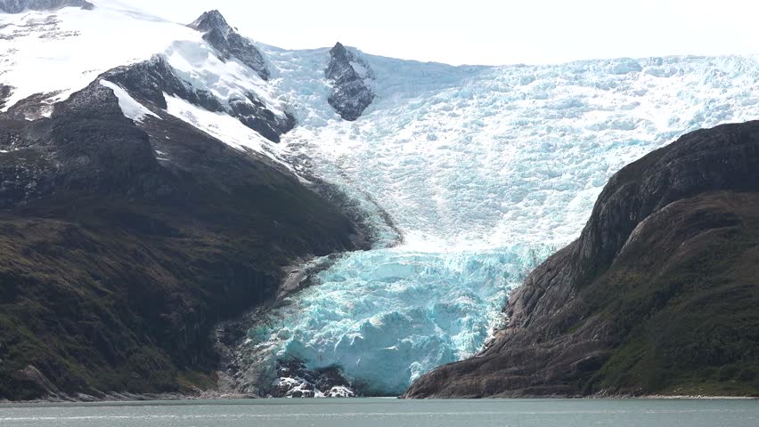 Majestic glacier with waterfall cascading down rocky cliffs in remote wilderness area