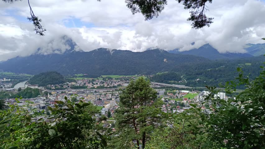 Scenic view of city nestled in valley surrounded by mountains and clouds in Switzerland during daytime