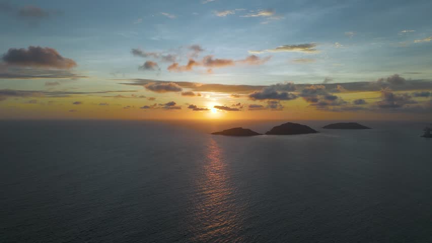 Breathtaking sunset over the Pacific Ocean in Mazatlan, Sinaloa, Mexico, with Deer Island and Bird Island bathed in golden light. The horizon glows as waves shimmer under the fading sun.