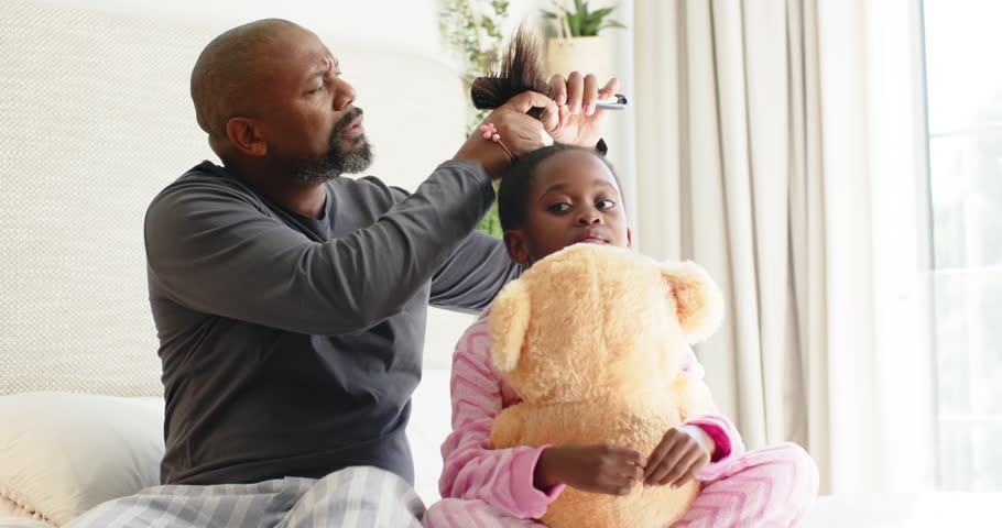 African American father picking comb, detangling daughter