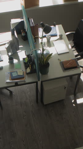 Vertical high angle shot of masked male criminal walking from desk to desk in office room searching for confidential corporate data looking through documents during industrial espionage