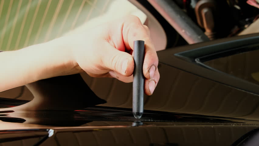 Automotive technician hits block with slide hammer removing dent. Technician holds block in hands and applies pressure to surface performing task