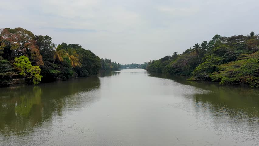 Wide scenic river lined with trees on riverbank in Galle Province in southern Sri Lanka