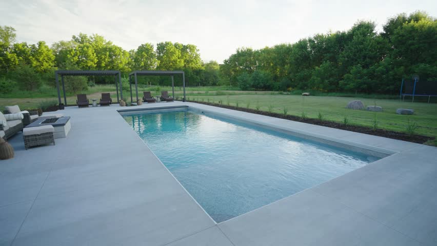 Contemporary residential patio with pergolas, lounge seating, and a fiberglass pool.