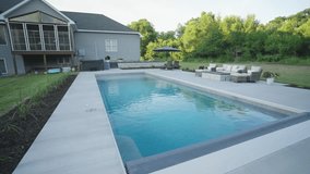 Wide view of luxury backyard fiberglass pool with retracted cover and patio furnishings. - Powered by Shutterstock - Get 15% off with code: PIKWIZARD15