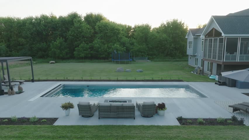 Balanced view of backyard pool and patio area with golden sunset and modern design.