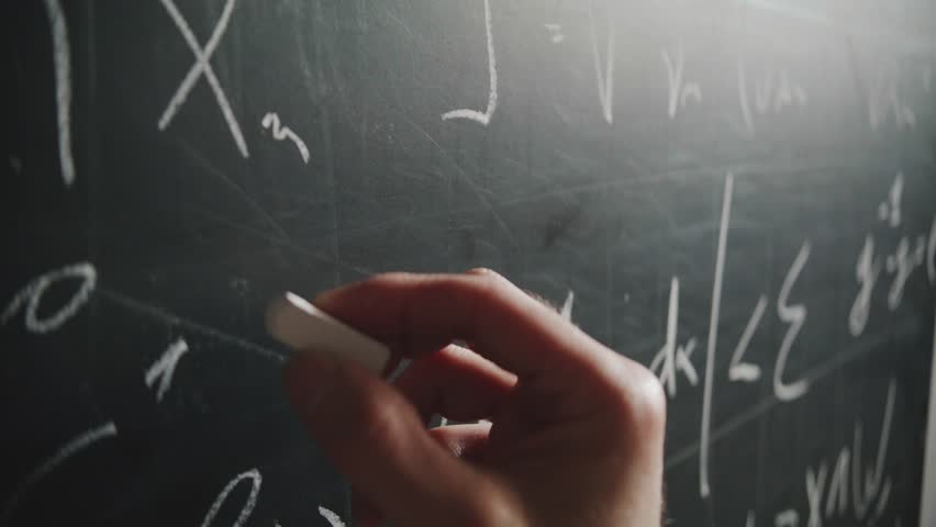 An extreme close-up, angled shot of a professor's hand writing a complex mathematical formula on a blackboard with chalk. A concept of science, education, and academia - Powered by Shutterstock - Get 15% off with code: PIKWIZARD15