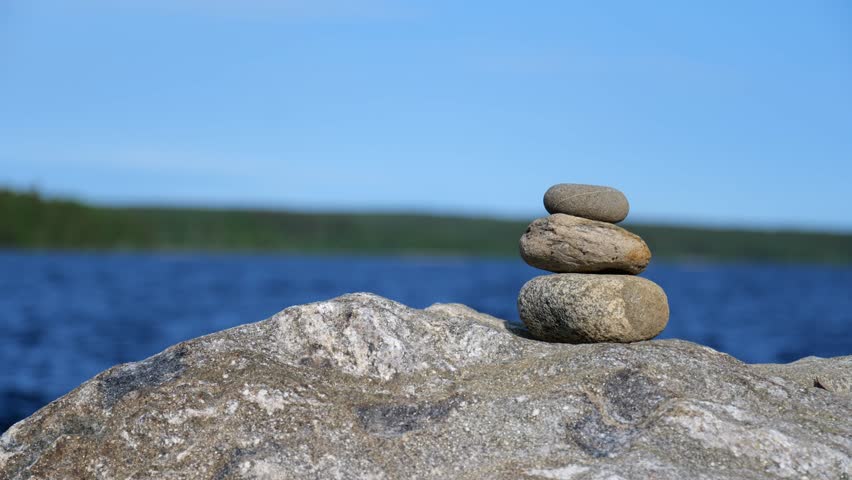 three rocks piled on each other. Peaceful lake scenery.