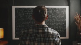 A scientist massages his tired neck, feeling the stress and pressure of solving complex mathematical formulas on a blackboard. A concept of burnout, fatigue, and difficult work - Powered by Shutterstock - Get 15% off with code: PIKWIZARD15