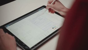 Over-the-shoulder shot of a person using a stylus to make notes and circle dates on a digital calendar app on a tablet. Concept of productivity, scheduling, and planning. - Powered by Shutterstock - Get 15% off with code: PIKWIZARD15
