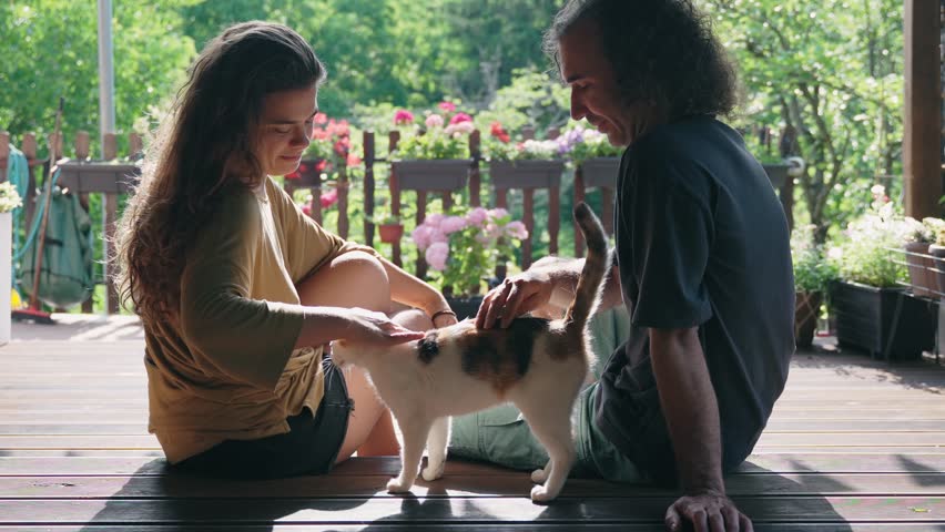 A young couple suffers from the fur of a molting cat while sitting on the terrace of a country house