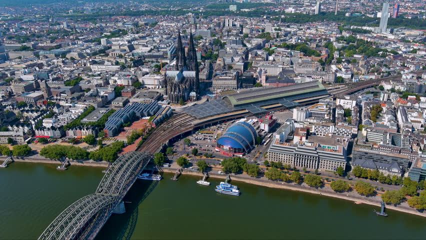 4K drone view of Cologne cityscape : Cologne Cathedral, Hohenzollern Bridge over the Rhine, central station and Musical Dome by the Old Town and riverside promenade on a clear summer day.