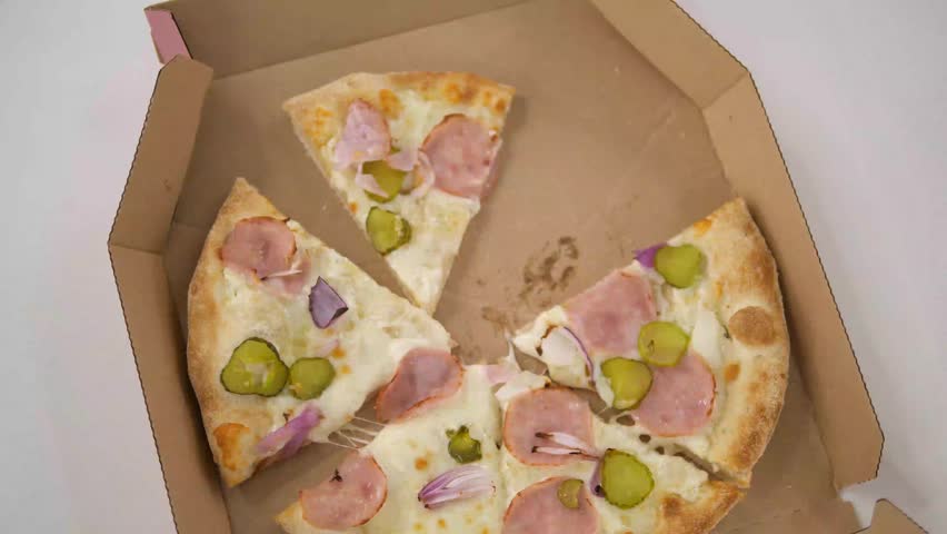  Female hand takes a slice of pizza from a box. Close-up, top view.