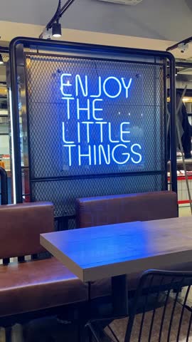 Neon sign with motivational quote in modern cafe setting with seating and industrial decor video